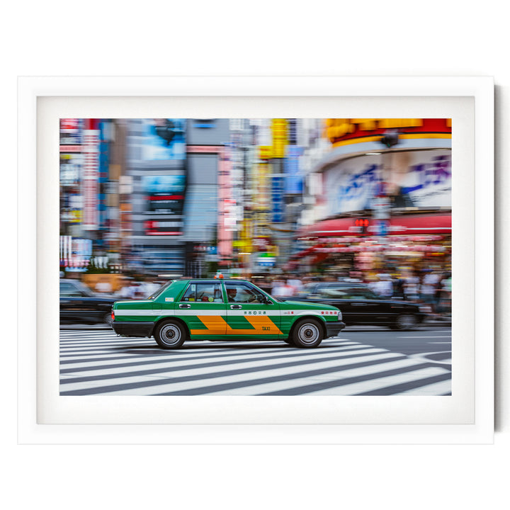 A green and yellow taxi cab is driving through a busy city street, with colorful buildings and billboards in the background.