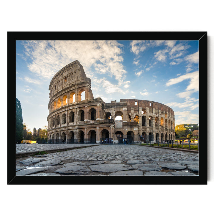 the Colosseum, an ancient amphitheater in Rome, Italy, with its distinctive oval shape and arches. The Colosseum is set against a backdrop of a blue sky with clouds, creating a picturesque scene.