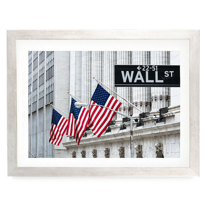 three American flags flying in front of a building with a black sign that reads "Wall St."