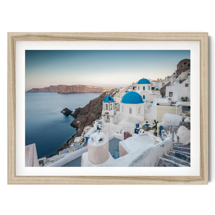 a picturesque coastal town with white buildings and blue domes, overlooking the ocean.