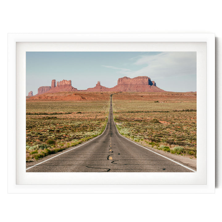 A long, straight road stretches out into the distance, leading towards a majestic mountain range in the background.