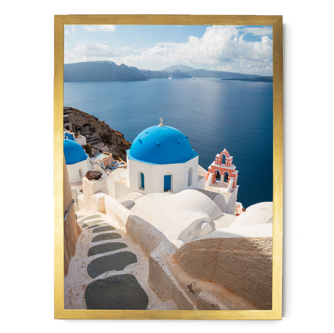 a picturesque view of a Greek island with white buildings and blue domes, overlooking the deep blue sea and a mountainous landscape in the distance.