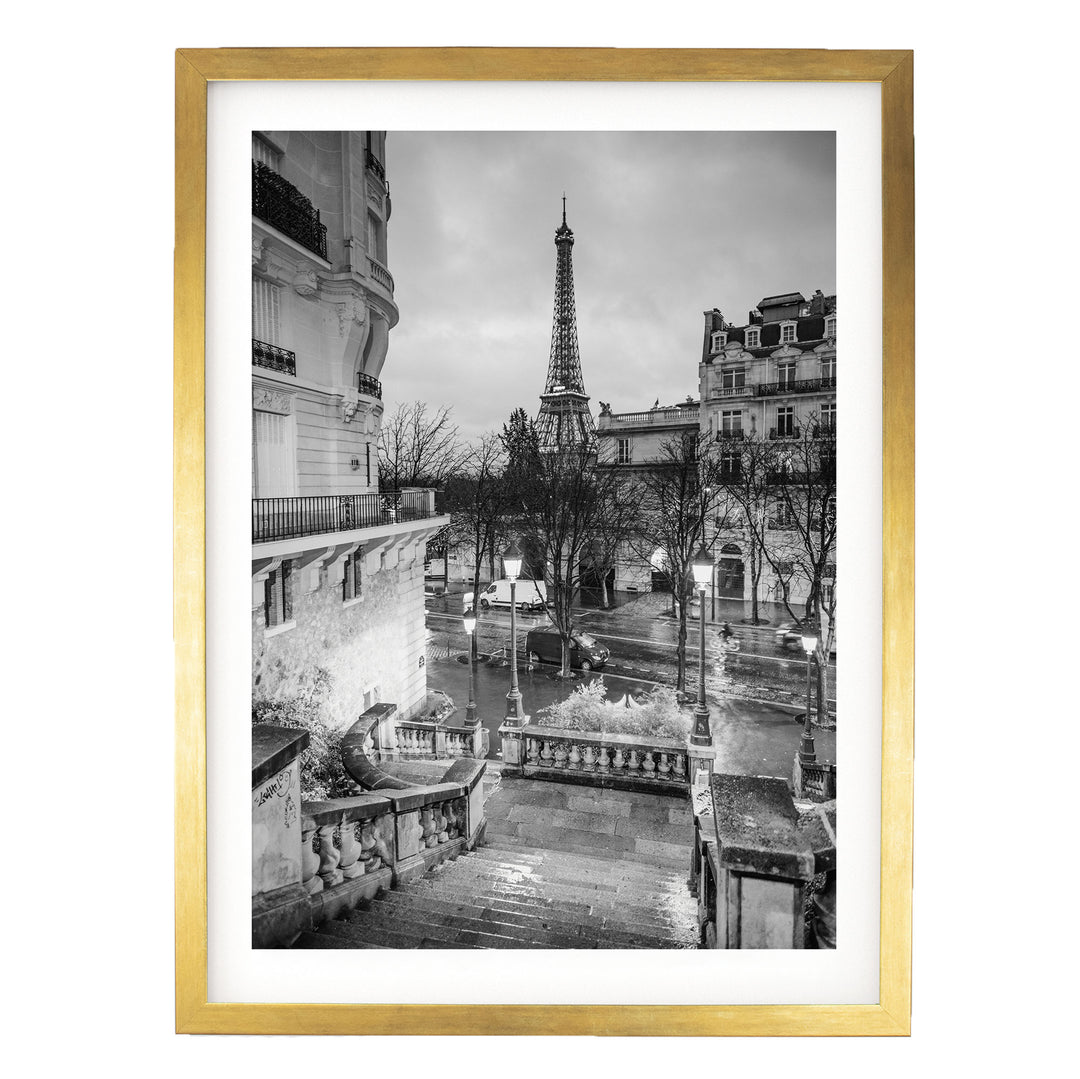 A black and white photograph of the Eiffel Tower in Paris, France, with a rainy cityscape in the background.