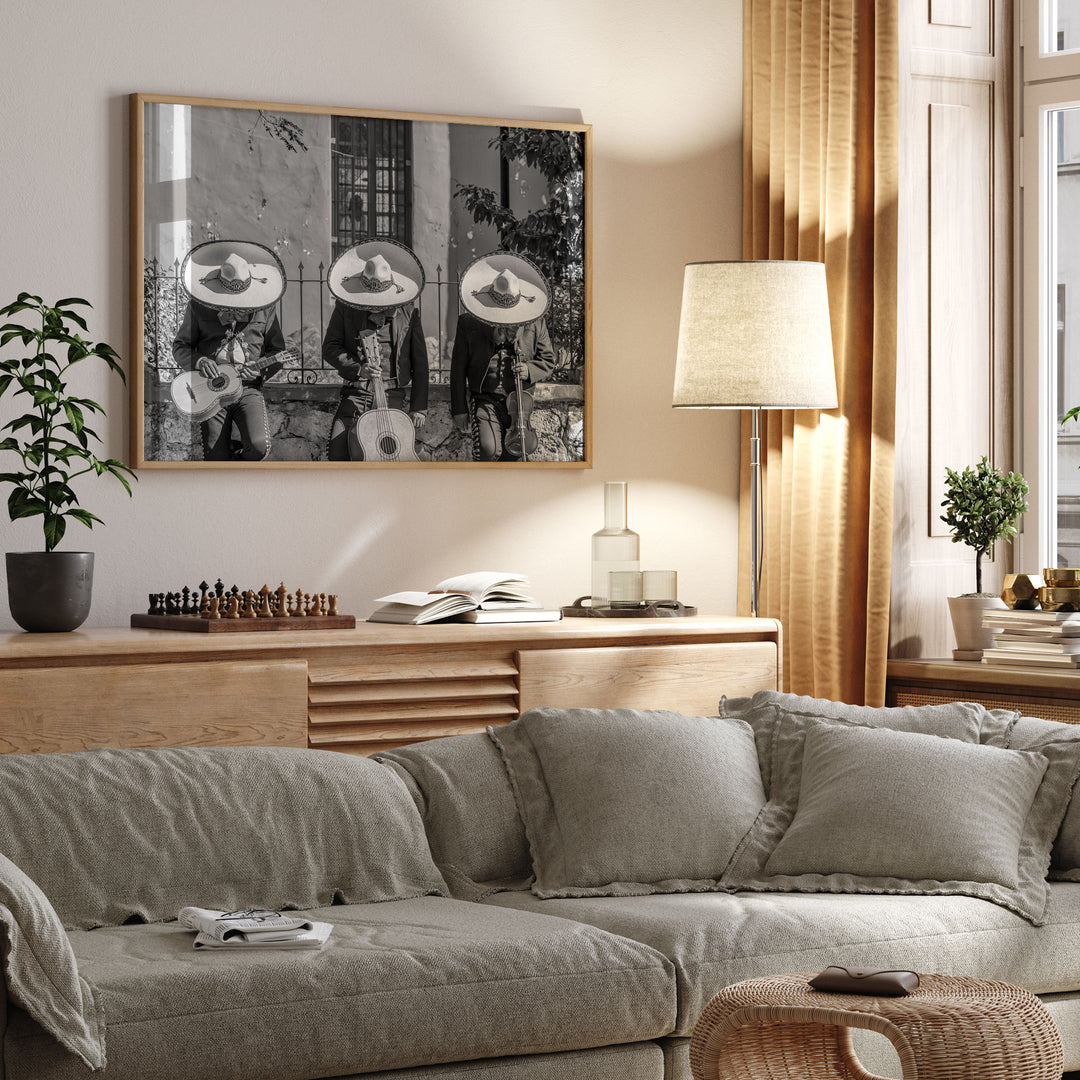 a cozy living room with a gray sofa, a wooden side table, and a framed black and white photograph of three musicians playing instruments. The room is decorated with a lamp, a potted plant, and a chess set on the side table.