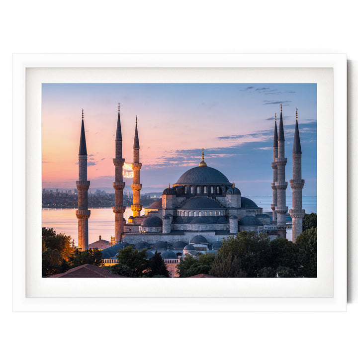 the Blue Mosque, also known as the Sultan Ahmed Mosque, in Istanbul, Turkey, with its distinctive minarets and domes silhouetted against a colorful sunset sky.
