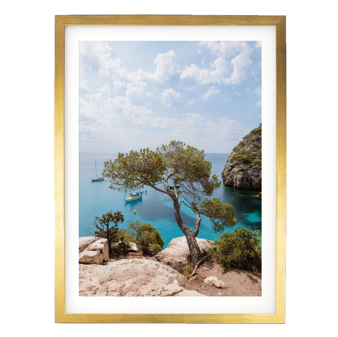 a scenic view of a rocky coastline with a large tree, a small boat, and a clear blue sky with clouds.