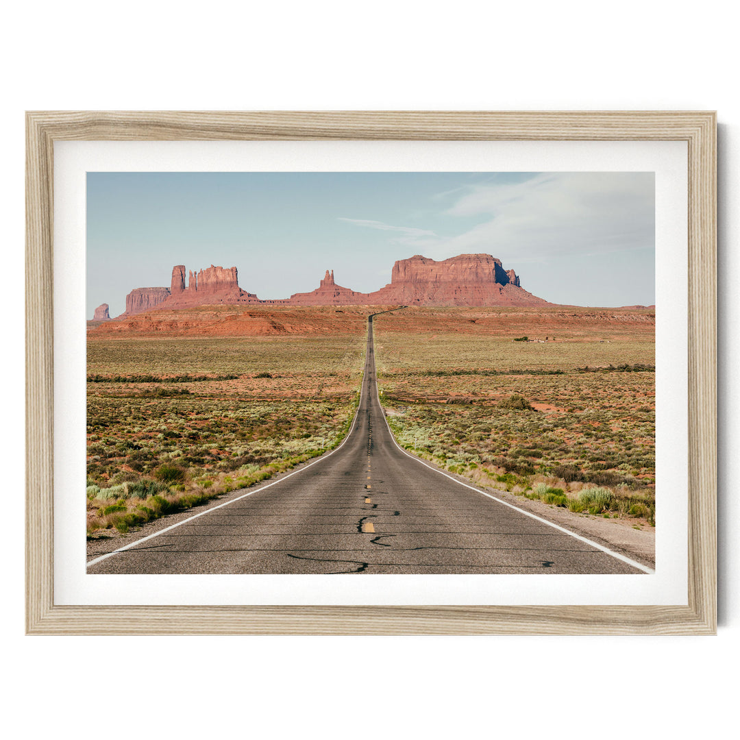 A long, straight road stretches out into the distance, leading towards a majestic mountain range in the background.