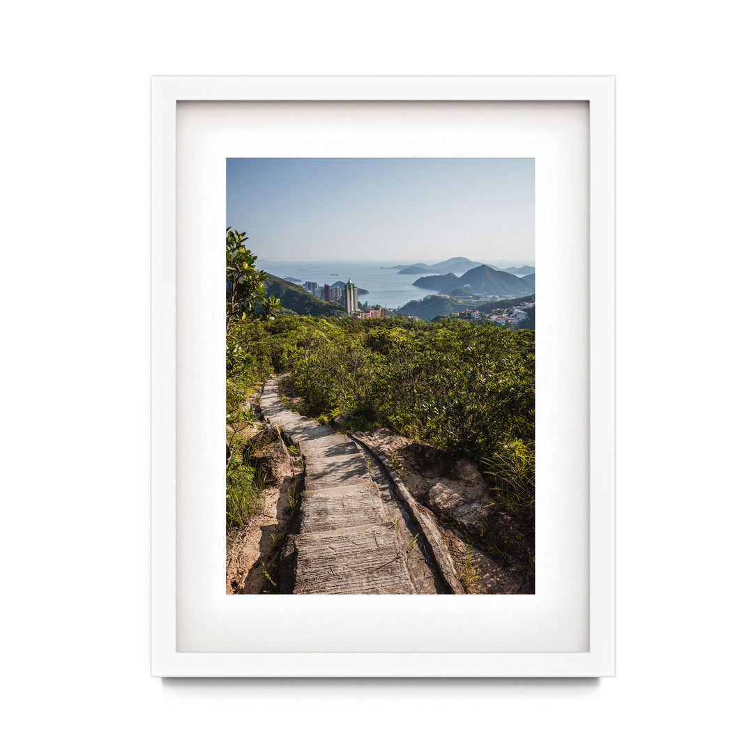 a framed photograph of a path leading to a city