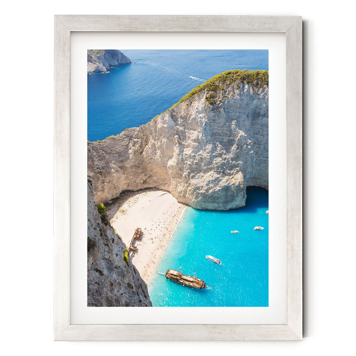 a picturesque coastal scene with a rocky cliff overlooking a turquoise sea dotted with boats.