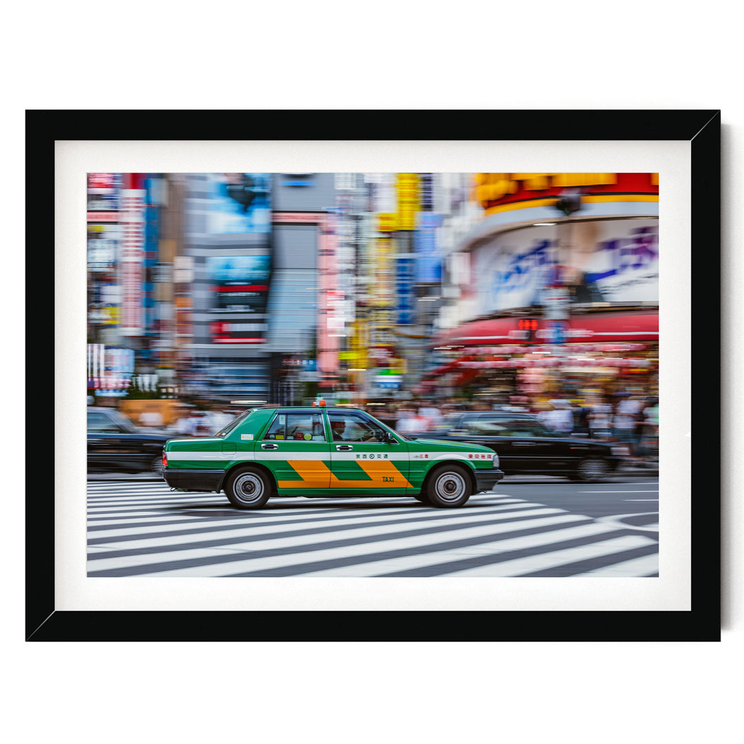 A green and yellow taxi cab is driving through a busy city street, with tall buildings and colorful signs in the background.