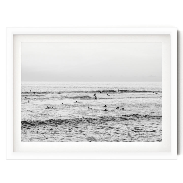 A group of people are enjoying the ocean waves, with some standing and others paddling on surfboards.