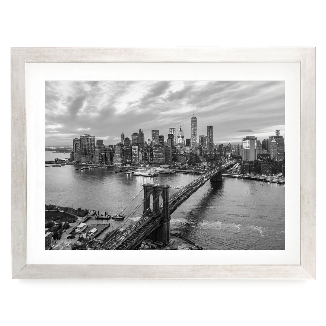 A black and white aerial view of the Manhattan skyline, showcasing the iconic Brooklyn Bridge and surrounding cityscape.
