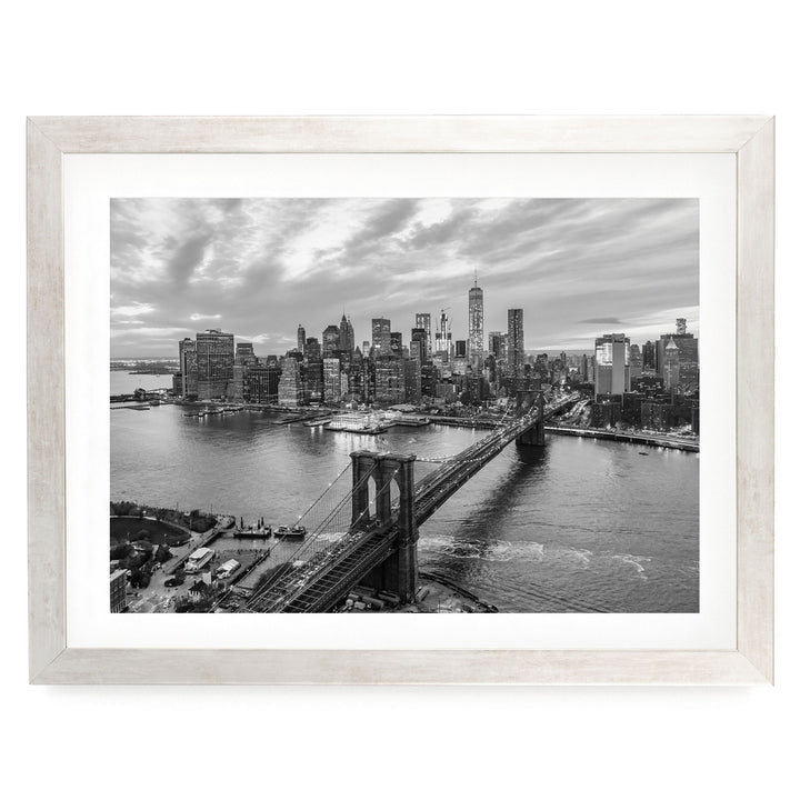 A black and white aerial view of the Manhattan skyline, showcasing the iconic Brooklyn Bridge and surrounding cityscape.
