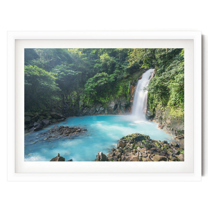 A serene waterfall cascades into a turquoise pool surrounded by lush, verdant foliage in a tranquil forest setting.