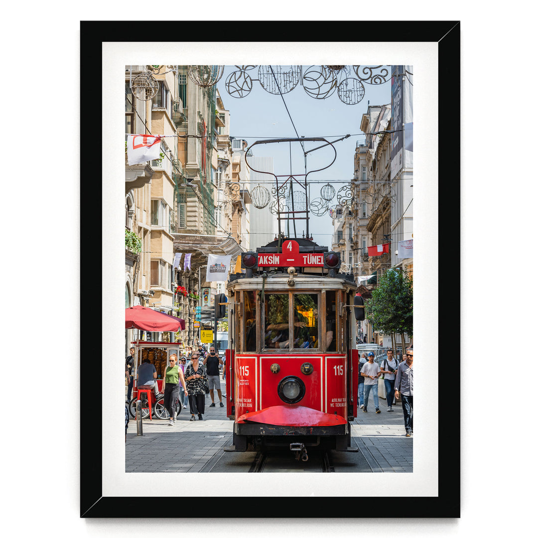 A red trolley car is traveling down a busy street in Istanbul, Turkey, surrounded by pedestrians and buildings.