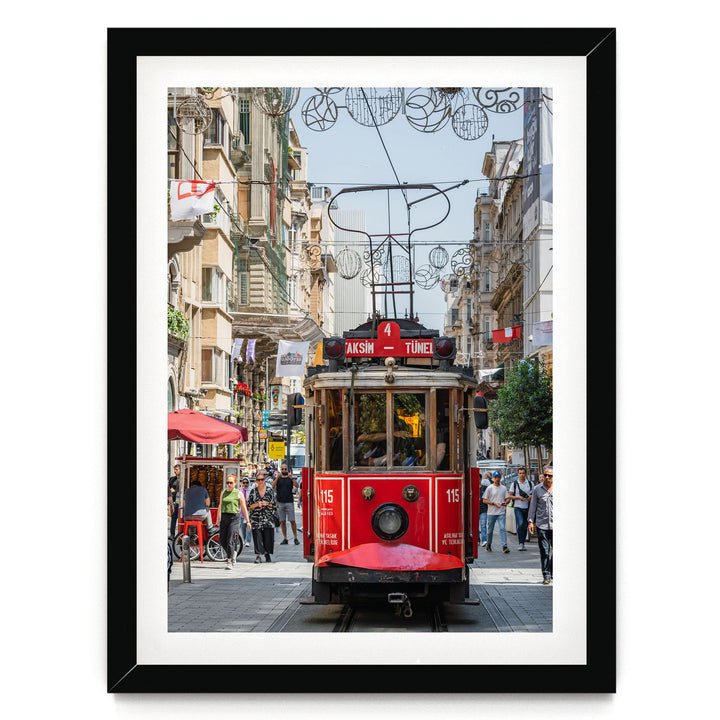 A red trolley car is traveling down a busy street in Istanbul, Turkey, surrounded by pedestrians and buildings.