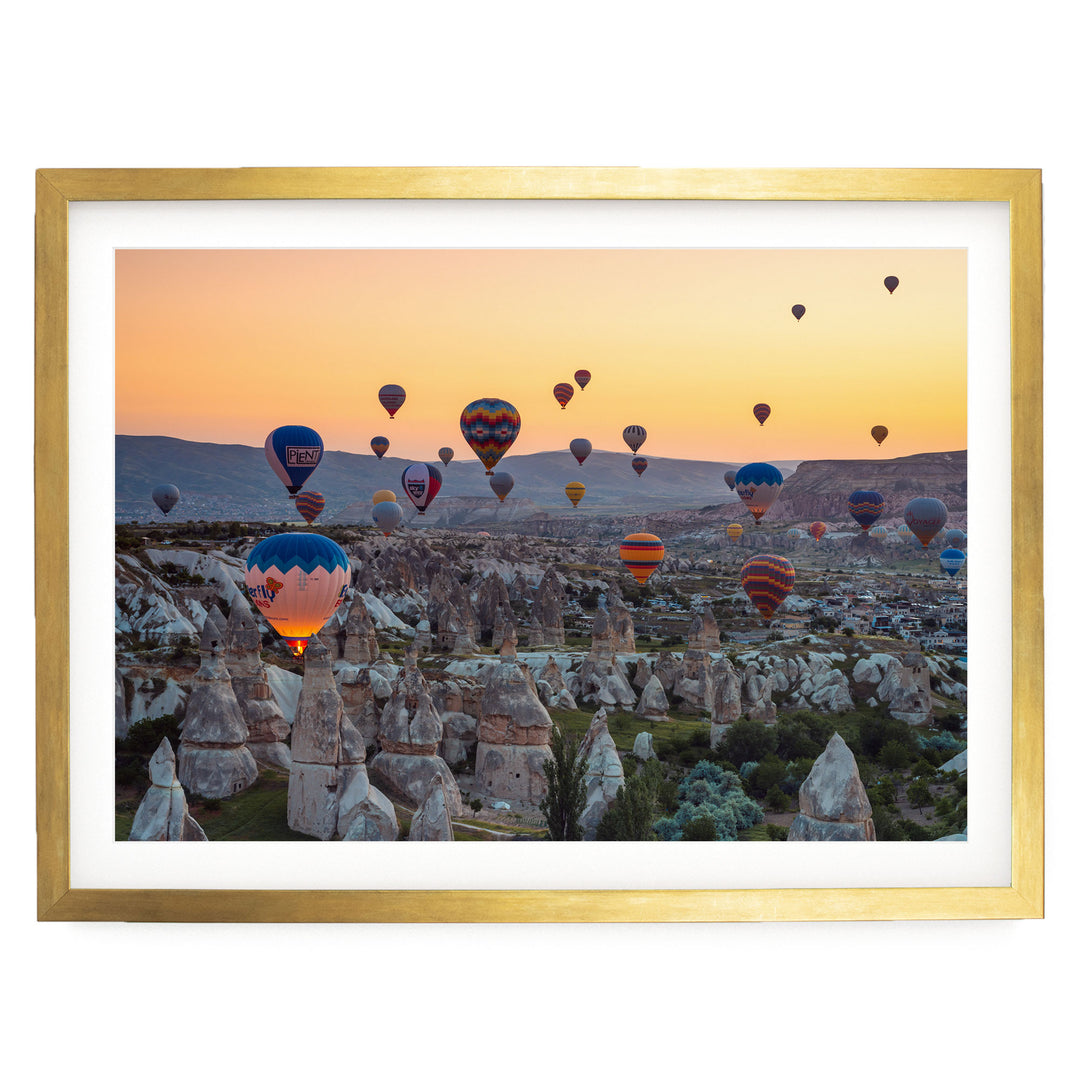 a breathtaking scene of hot air balloons floating over a rocky landscape at sunset.