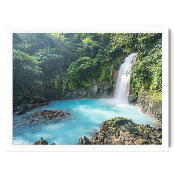 A serene waterfall cascades into a turquoise pool surrounded by lush, verdant foliage in a tranquil natural setting.