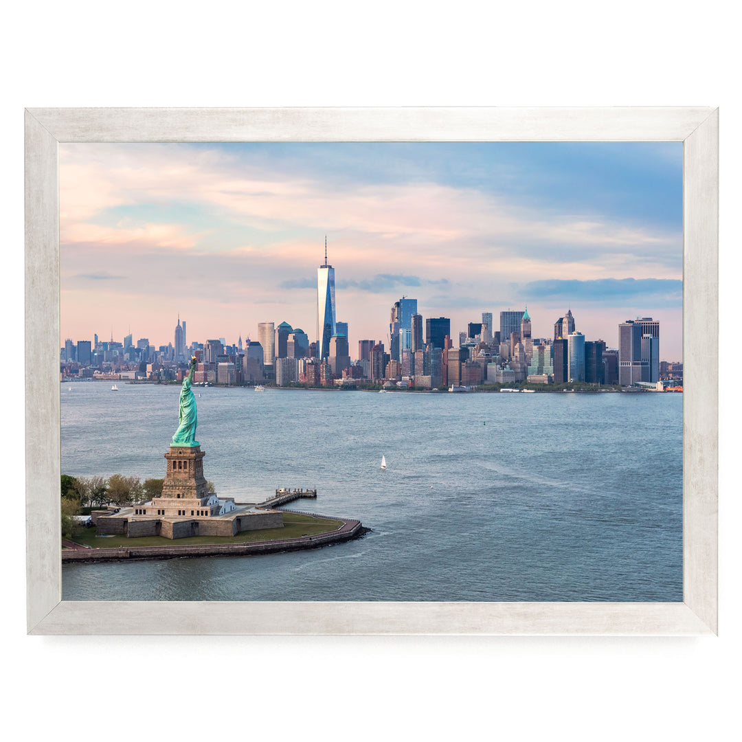 the Statue of Liberty on a small island in the foreground, with the New York City skyline in the background.