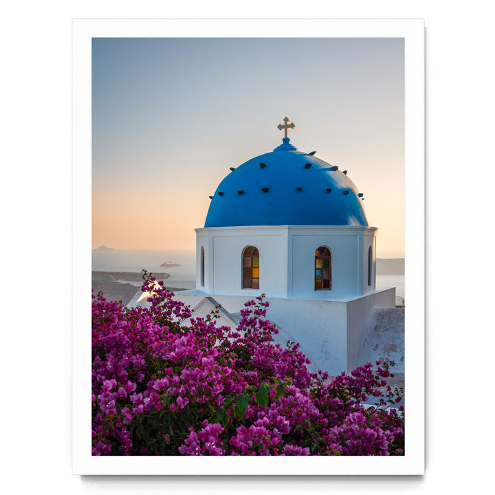 a blue-domed church with a cross on top, surrounded by a vibrant display of purple flowers.