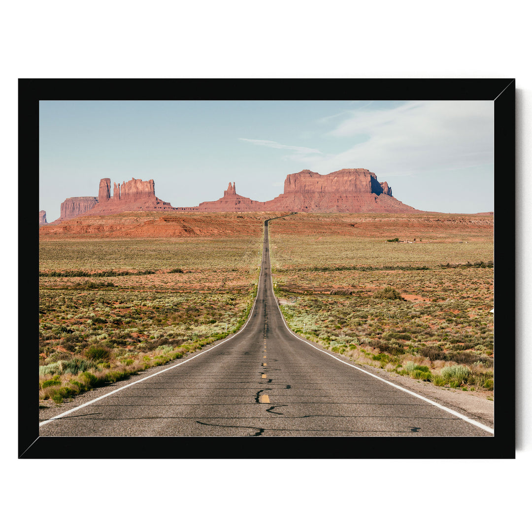 A long, straight road stretches out into the distance, leading towards a majestic mountain range in the background.