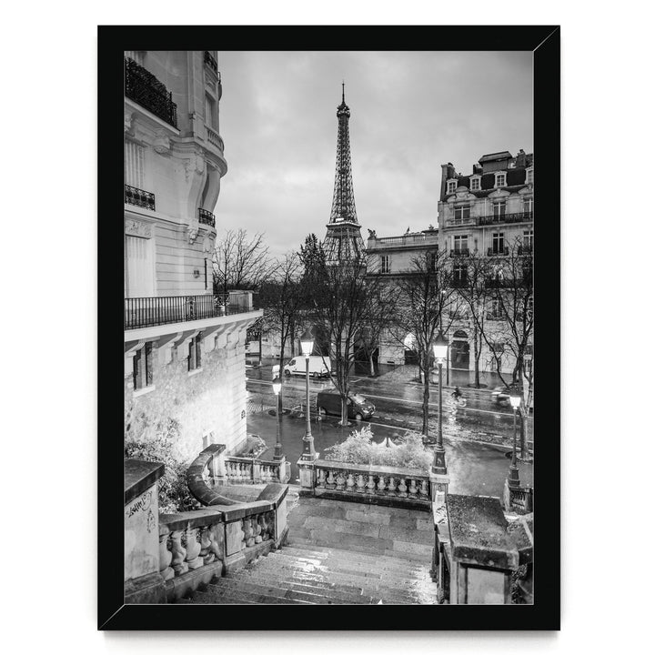 A black and white photograph of the Eiffel Tower in Paris, France, with the surrounding buildings and streets visible.