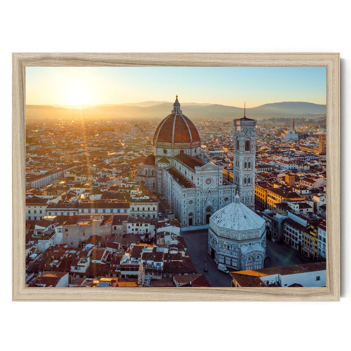 a cityscape with a large domed building, possibly a cathedral or church, surrounded by smaller buildings and structures. The sun is setting, casting a warm glow over the scene and creating a picturesque view of the city.