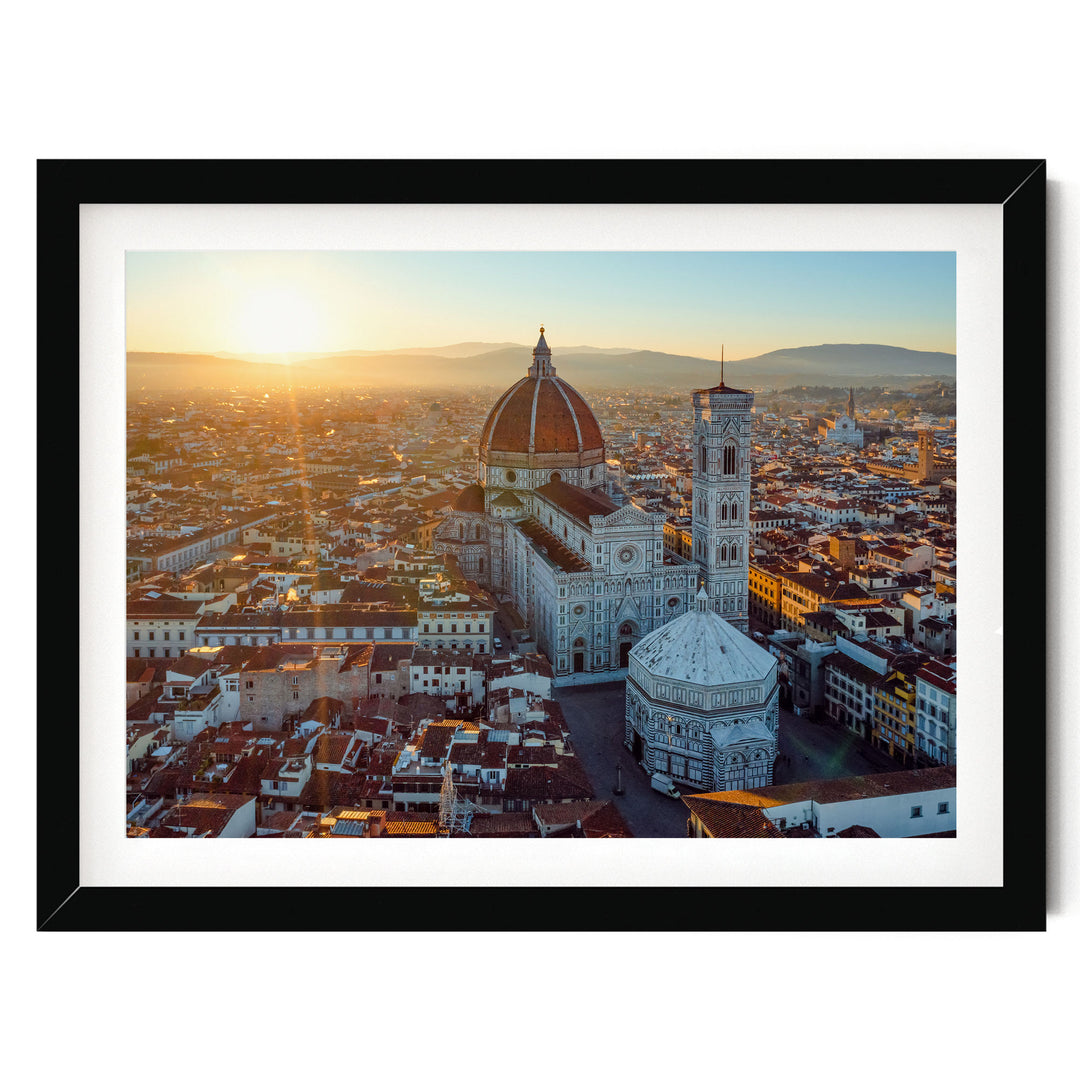 the Florence Cathedral, also known as the Cathedral of Saint Mary of the Flower, in the heart of Florence, Italy. The cathedral is a prominent landmark in the city, with its distinctive dome and bell tower standing out against the backdrop of the cityscape. The sun is setting, casting a warm glow over the scene and highlighting the architectural details of the cathedral.