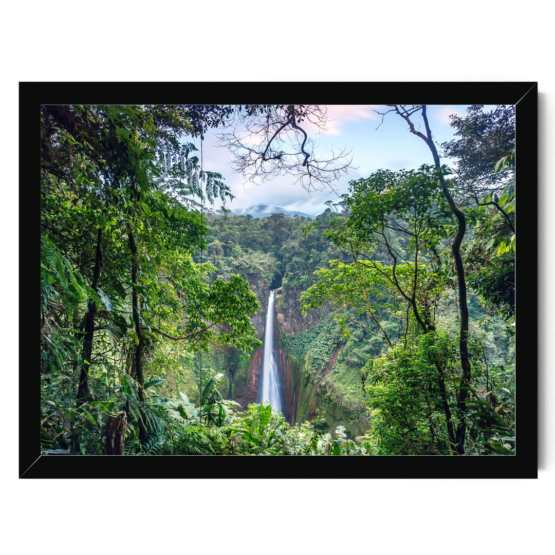 A lush, verdant forest with a towering waterfall cascading down the rocky cliff face, framed within a black border.