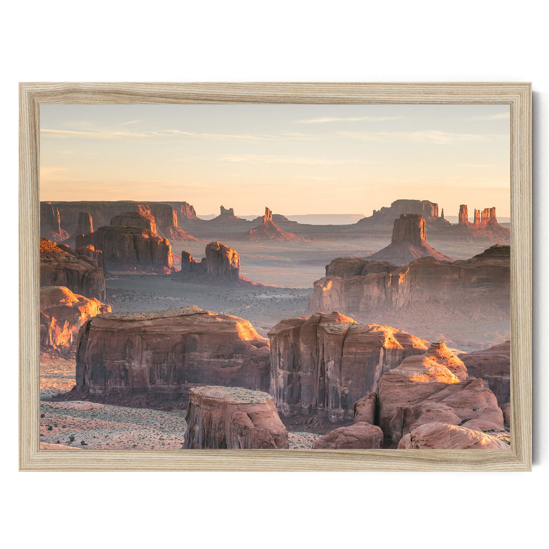 a breathtaking view of the Grand Canyon, with its towering red rock formations bathed in the warm glow of the setting sun. The sky above is a beautiful canvas of orange and pink hues, creating a stunning backdrop for the natural landscape. The image is framed, adding a touch of elegance to the scene.