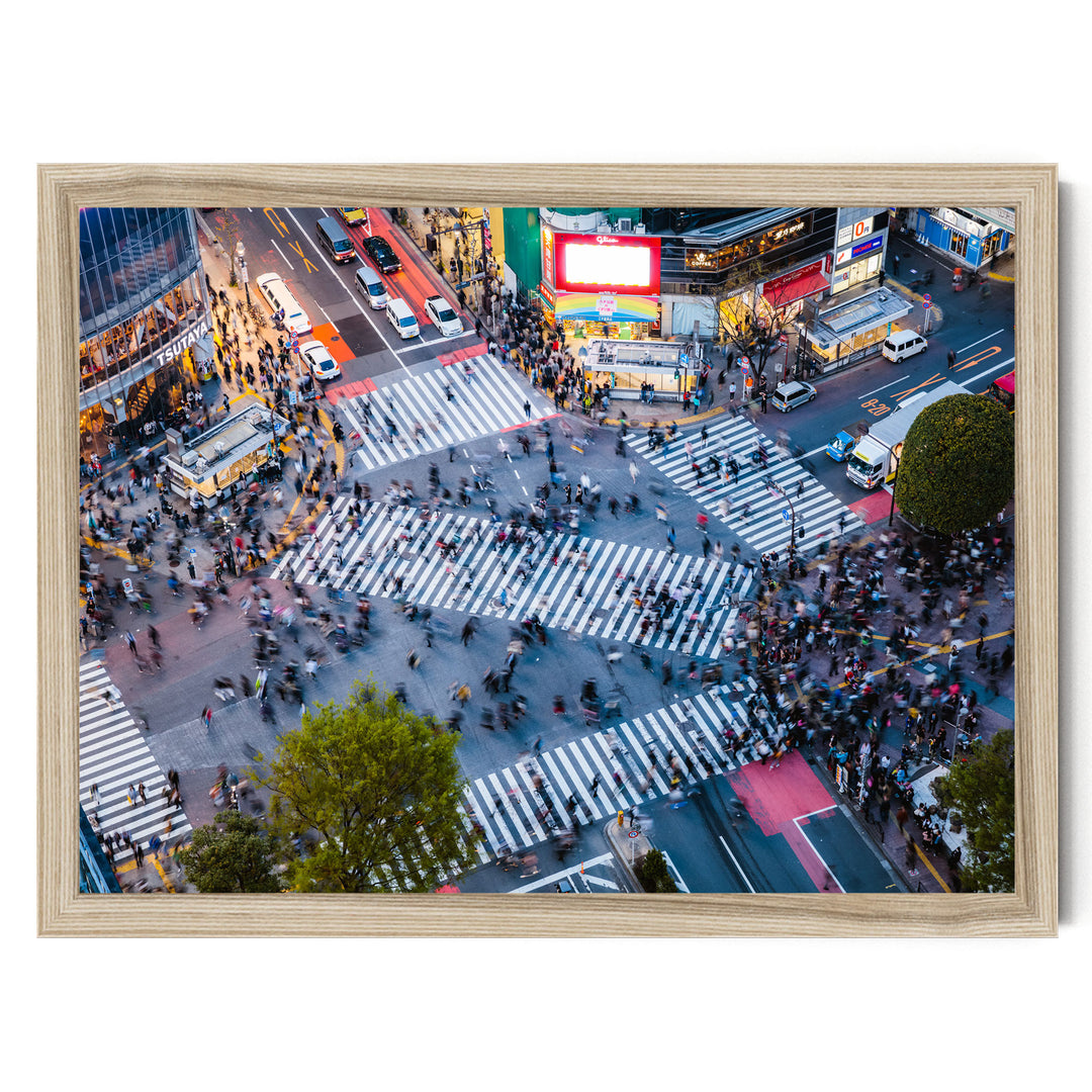 a busy city intersection with a large crowd of people crossing the street, surrounded by various vehicles and buildings.
