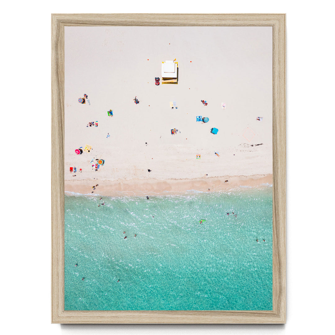 a beach scene with people enjoying the sun and water, featuring a clear blue sky and turquoise water.