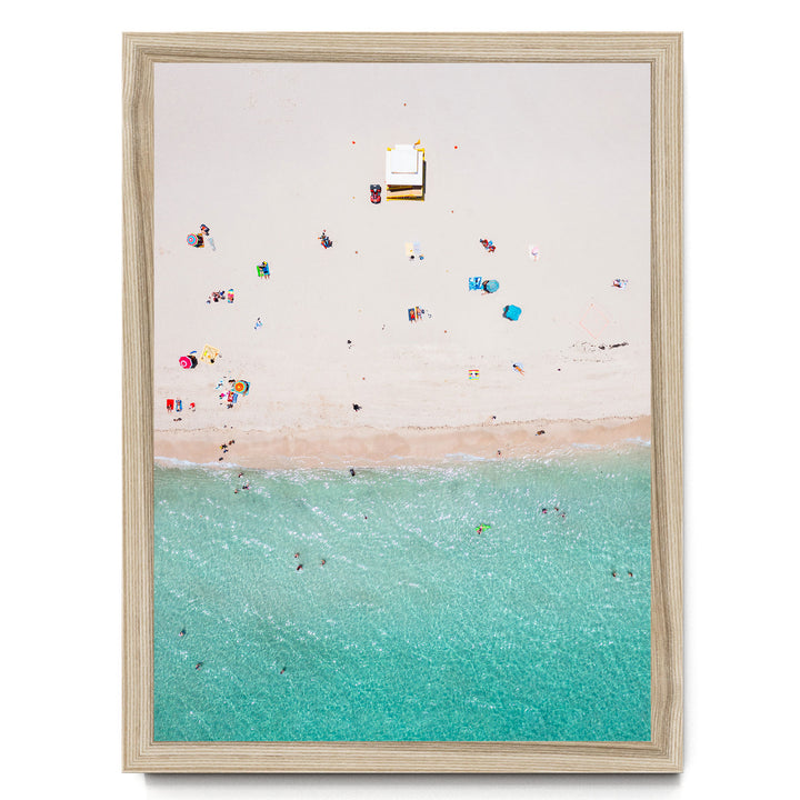 a beach scene with people enjoying the sun and water, featuring a clear blue sky and turquoise water.