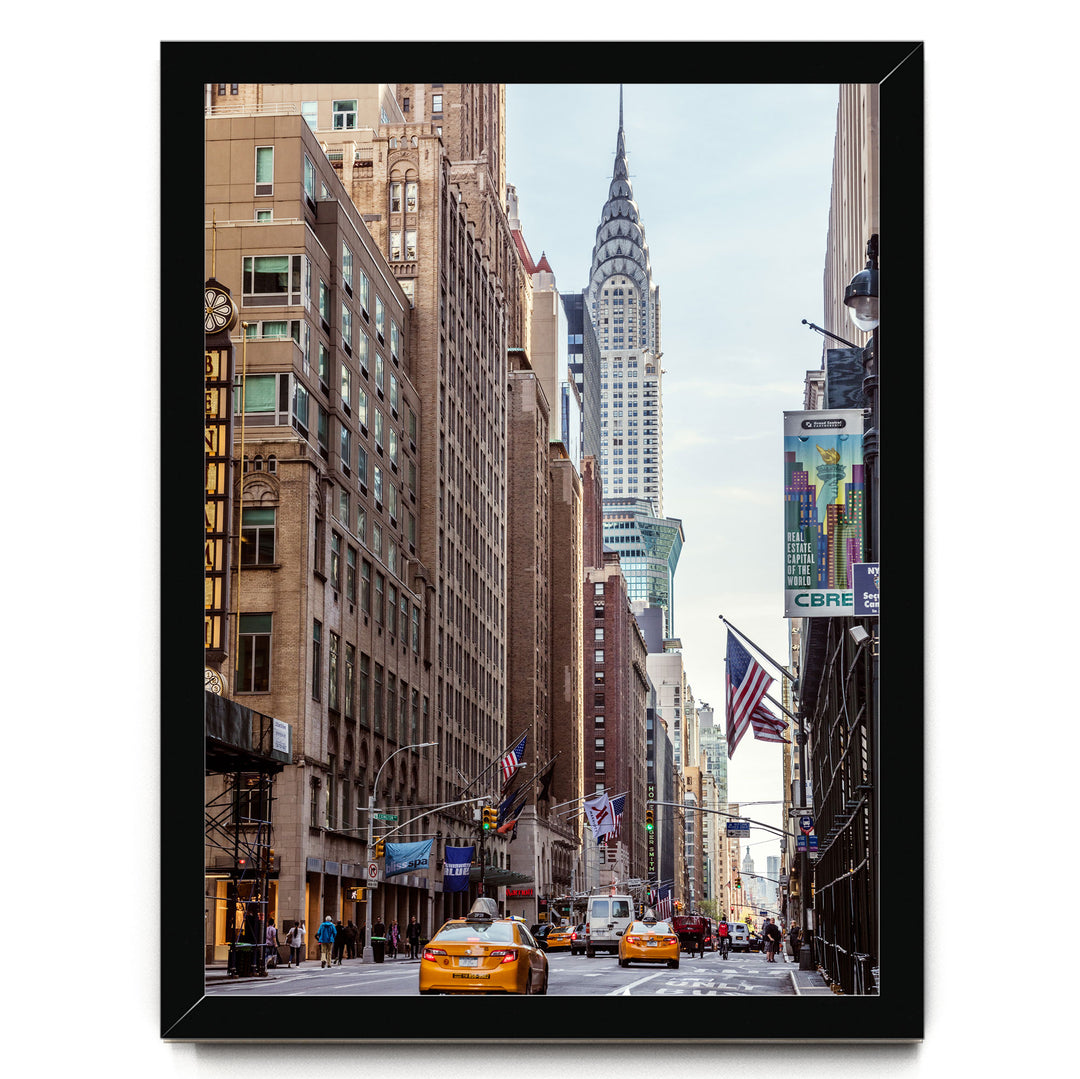 a busy city street with tall buildings, including the iconic New York City skyline, including the distinctive spire of the Chrysler Building.