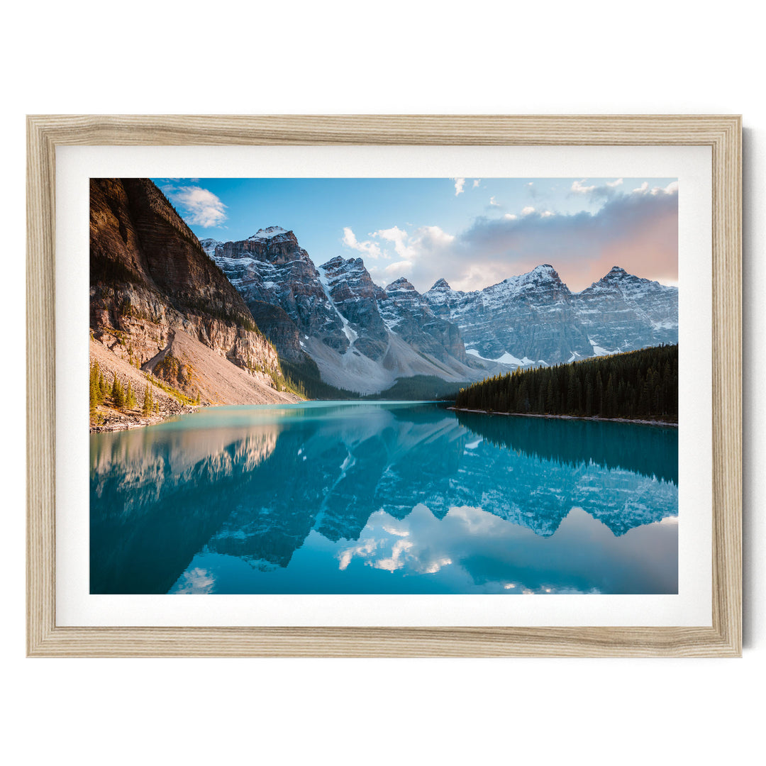 A framed photograph depicting a serene mountain landscape with a deep blue lake reflecting the surrounding peaks and sky.