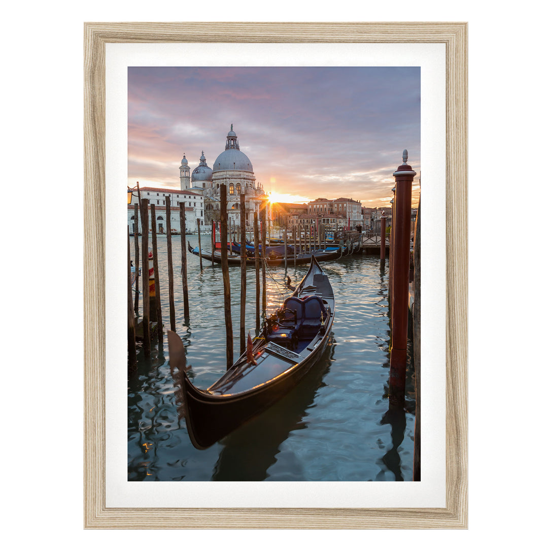a serene scene of a gondola floating on the water, with a picturesque view of the city skyline and the sun setting in the background.