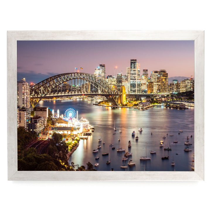 a city skyline at night, with a large bridge spanning a river filled with boats. The city is illuminated by the lights of the buildings, creating a vibrant and lively atmosphere.