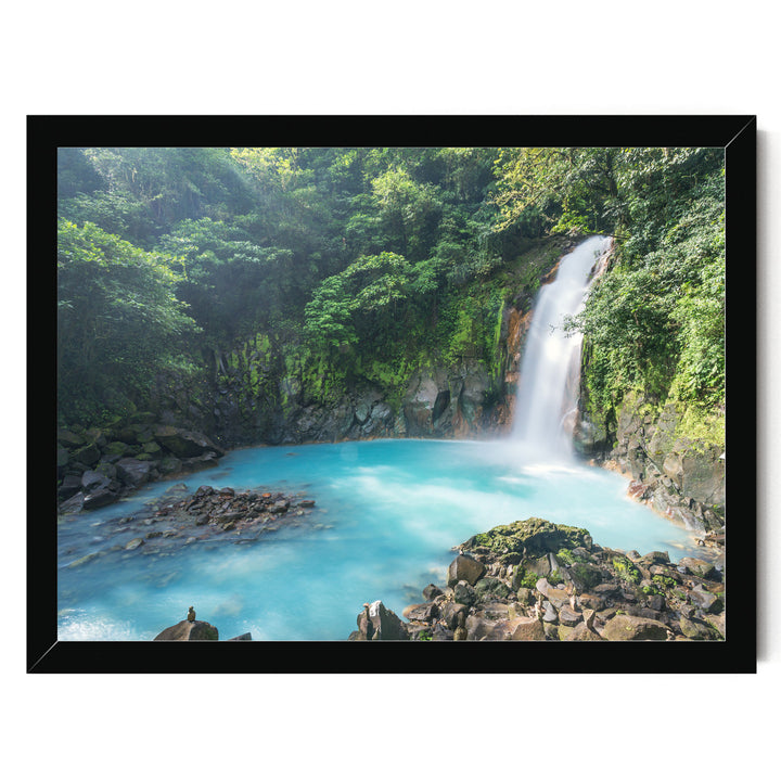 A serene waterfall cascades into a turquoise pool surrounded by lush, verdant foliage in a tranquil forest setting.