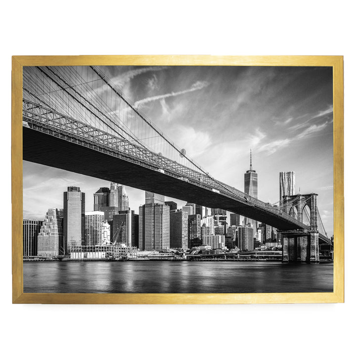 A black and white photograph of the Brooklyn Bridge in New York City, with the city skyline visible in the background.