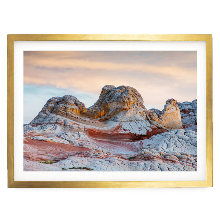 a striking natural landscape with a large, multi-layered rock formation in the foreground, set against a vibrant sky with a gradient of orange and pink hues.