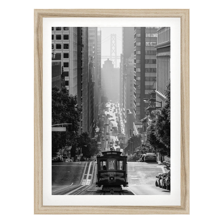 A black and white photograph of a trolley car traveling down a busy city street, surrounded by tall buildings and traffic.