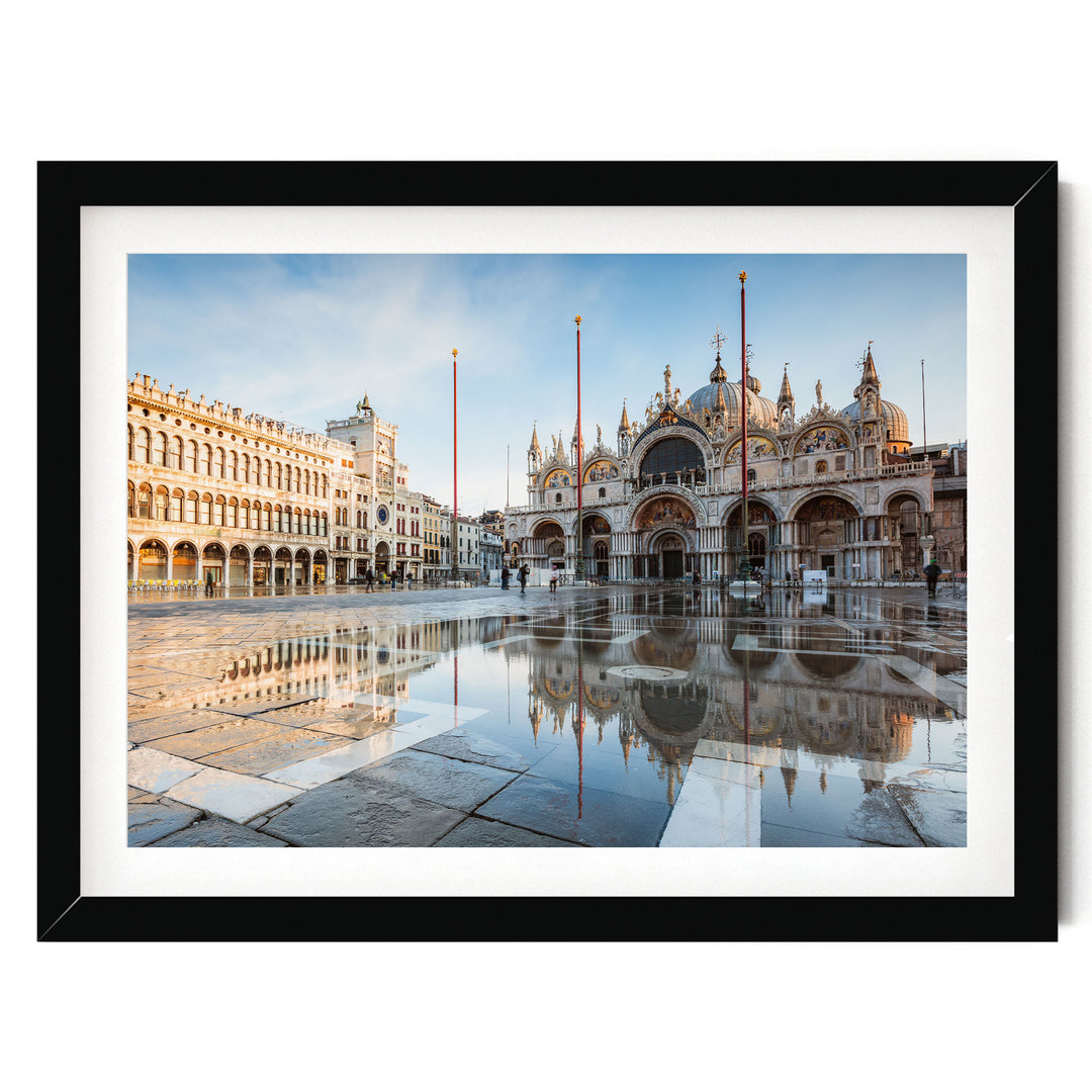 a large, ornate building with arched windows and a domed roof, situated in a square with a fountain in the foreground. The building is reflected in the water, creating a symmetrical and visually striking scene.