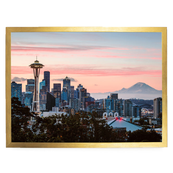 a cityscape with a tall tower, likely the Space Needle, against a backdrop of a colorful sunset sky and a distant mountain.