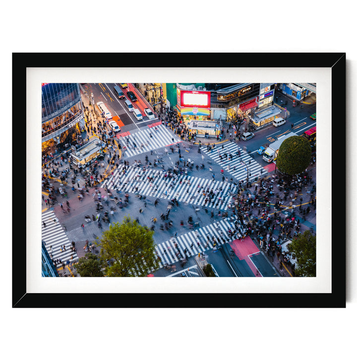 a busy city intersection with a large crowd of people crossing the street, surrounded by tall buildings and illuminated by colorful lights.