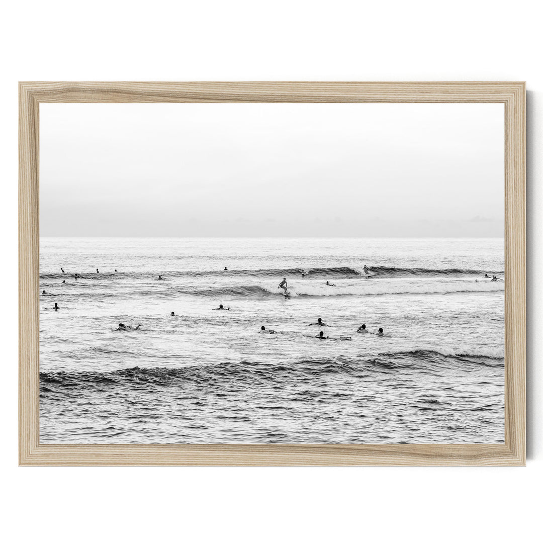 A group of people are enjoying the ocean waves, with some standing and others paddling on surfboards.