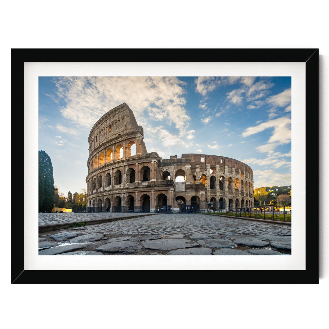 the Colosseum, an ancient amphitheater in Rome, Italy, with its distinctive oval shape and arches. The Colosseum is surrounded by a cobblestone courtyard, and the sky above is blue with some clouds. The photograph is framed and appears to be a collage of multiple images.
