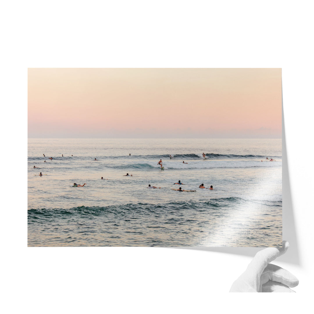 a group of people swimming and surfing in the ocean, with waves visible in the background.