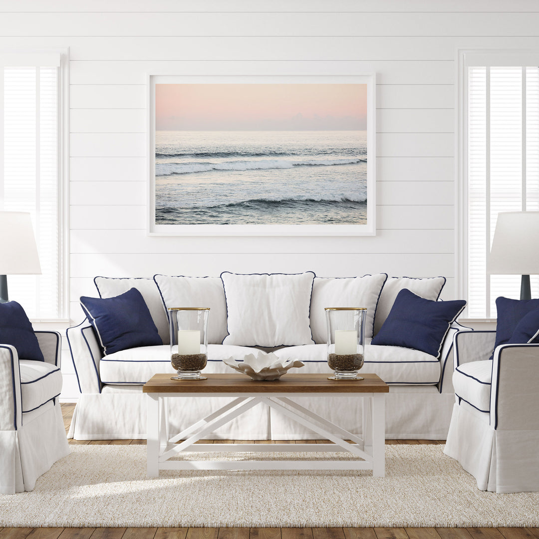 a serene living room with a white sofa, a wooden coffee table, and a framed picture of the ocean on the wall.