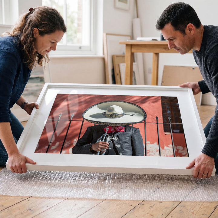 Couple placing a framed Mexican charro print in a room
