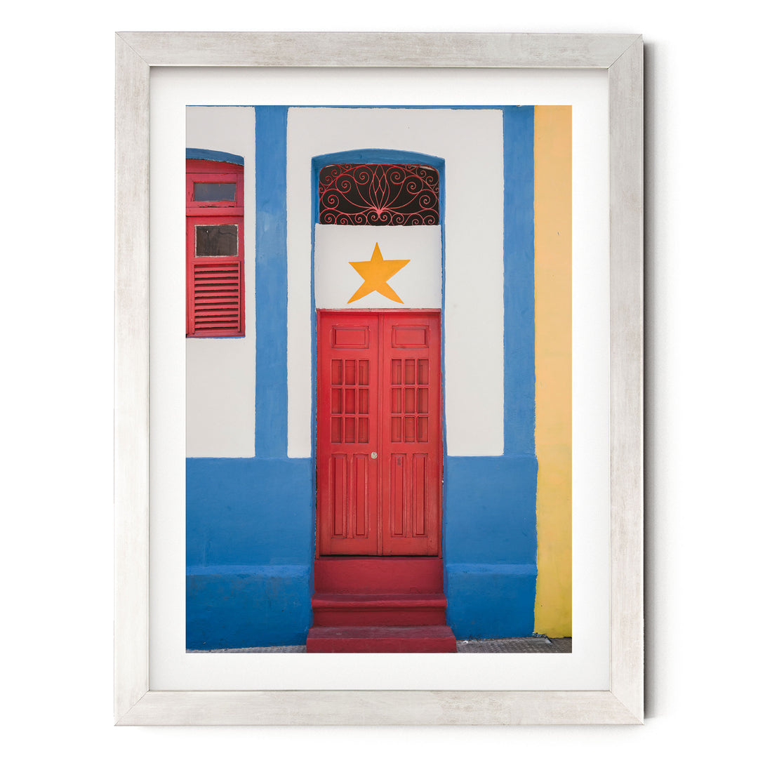 Red Door with Yellow Star, Olinda, Brazil print in a silver frame with white mat